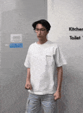 a man wearing glasses and a white shirt stands in front of a sign that says kitchen toilet