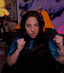 a woman wearing headphones is sitting in a chair with her eyes closed and her fist in the air .