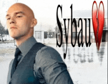 a bald man in a suit and tie is standing in front of a sign that says sybau