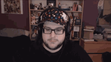 a man wearing headphones and a hat with the number 1 on it looks at the camera