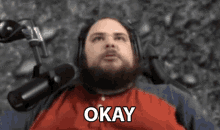 a man with a beard and headphones is sitting in front of a microphone .