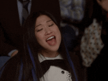 a woman wearing a tuxedo and a bow tie is smiling