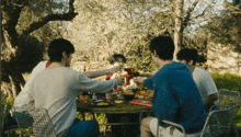 a group of people sitting around a table with food