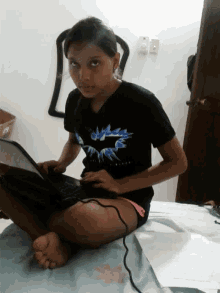 a girl is sitting on a bed using a laptop