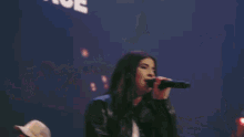 a man singing into a microphone on a stage with a sign that says the lord is in this place