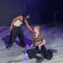 two women are dancing on a stage and one is kneeling down