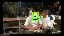 two men are cooking in a kitchen and one has a green pixelated face on his head .