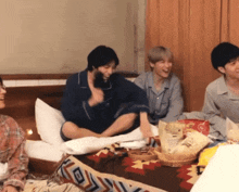 a group of young people are sitting on a bed with a bag of chips that says ' potato chips ' on it