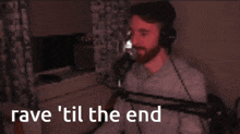a man wearing headphones singing into a microphone with the words rave 'til the end behind him