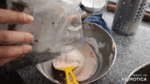 a person is pouring liquid into a bowl with a yellow spatula ..