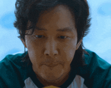 a close up of a man 's face with a green shirt on