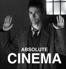 a man in a suit and tie stands in front of a sign that says " absolute cinema "