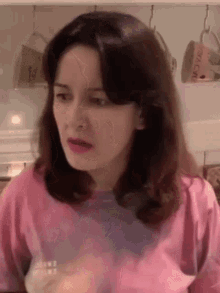 a woman in a pink shirt is looking at the camera .