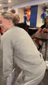 a woman wearing a grey sweatshirt is kneeling down