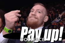 a man with a beard and a green wristband that says ufc on it is giving a pay up sign