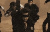 a group of people are running through a sandy field