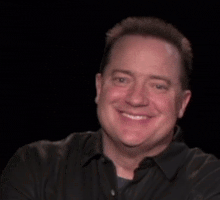 a man in a black shirt is smiling with the words look at behind him