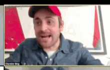 a man wearing a red hat is talking on a video call with chandler ring .