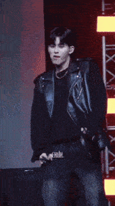 a man wearing a black leather jacket is dancing on stage