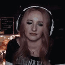a woman with pink hair is wearing headphones and making a funny face .
