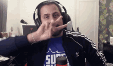 a man wearing headphones and a blue shirt that says super on it