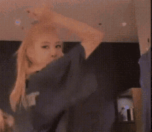 a woman is dancing in a room wearing a shirt that says ' x ' on it .