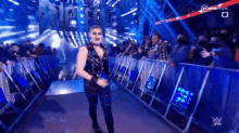 a woman in a black outfit is walking down a ramp in front of a crowd of people .