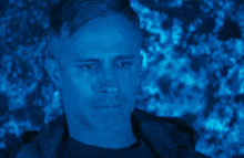 a man is crying in a dark room with a blue background