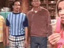 a group of people are standing in a kitchen .