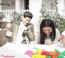 a man and a woman are sitting at a table with colorful lego blocks and a ifafooz tv logo behind them
