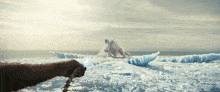 a person is holding a chain in front of a large iceberg