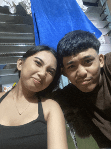 a man and a woman pose for a picture in front of a blue towel