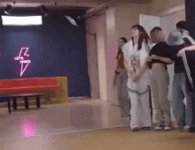 a group of people are standing in a room with a lightning bolt sign on the wall .