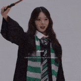 a girl in a harry potter costume is holding a wand in her hand and the words dxnzzi are below her