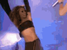 a woman in a crop top is dancing in front of a blue background