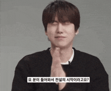 a man wearing a black sweater is making a gesture with his hands