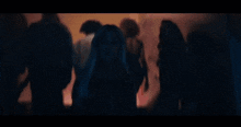 a crowd of people are gathered in a dark room with a blue light coming out of the ceiling .