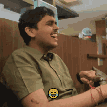 a man in a green shirt is laughing with a yellow smiley face on his arm