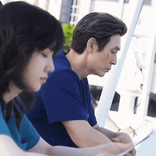 a man in a blue shirt is sitting next to a woman