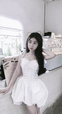 a woman in a white dress is standing in front of a sign that says " tam ca pho "