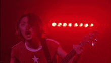 a man with long hair and a beard is playing a guitar in a red light