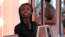 a woman wearing a head scarf looks at the camera while sitting at a desk