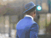 a man in a blue suit and hat is waiting at a traffic light