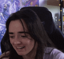 a close up of a woman sitting in a chair with her eyes closed and smiling .