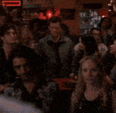 a group of people are gathered in a dark room with a neon sign that says ' a few dollars ' on it