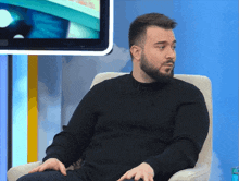a man with a beard is sitting in a chair