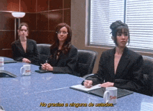 three women are sitting at a conference table and one of them says no gracias a ninguna de ustedes in yellow letters
