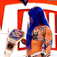 a female wrestler with blue hair is holding a championship belt
