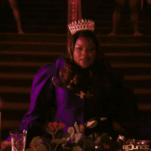 a woman with a crown on her head is sitting at a table with a sign that says bounce