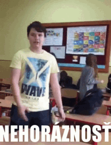a boy wearing a yellow wave shirt stands in a classroom